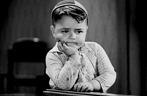 Little boy in a black and white film resting his chin on his hand, bored and waiting