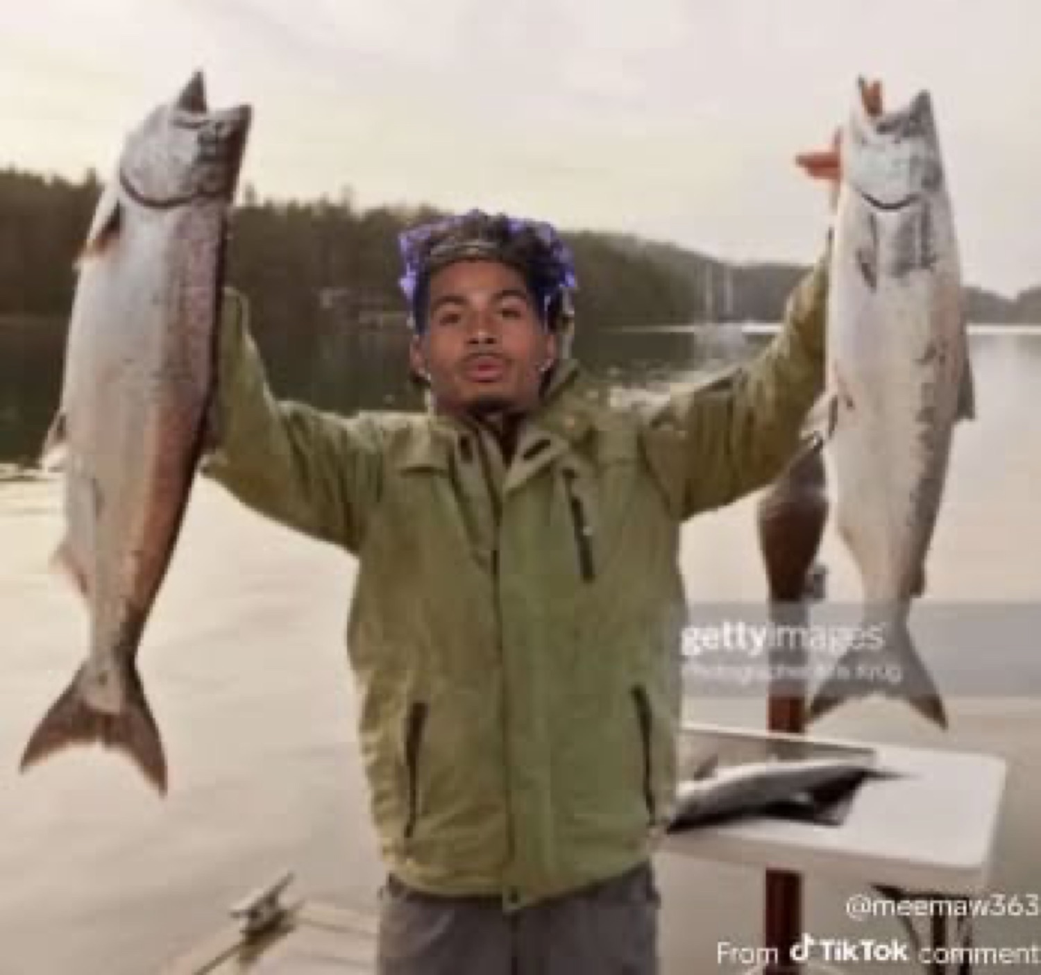 Man proudly holding up a fish in each hand, the 'two fishes' meme
