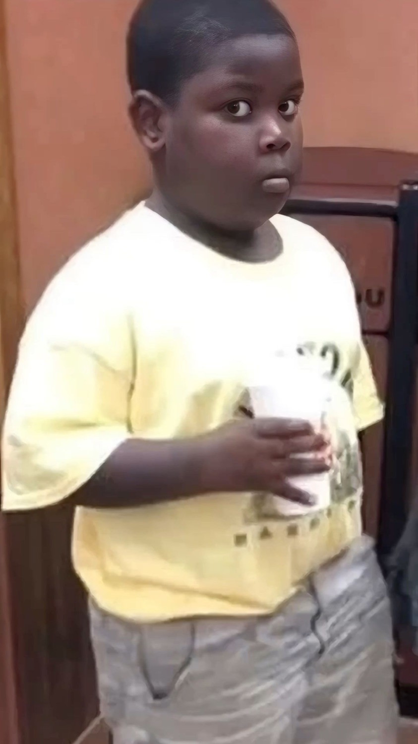 Kid clutching a drink cup, frozen mid-sip with a wide caught-in-the-act stare