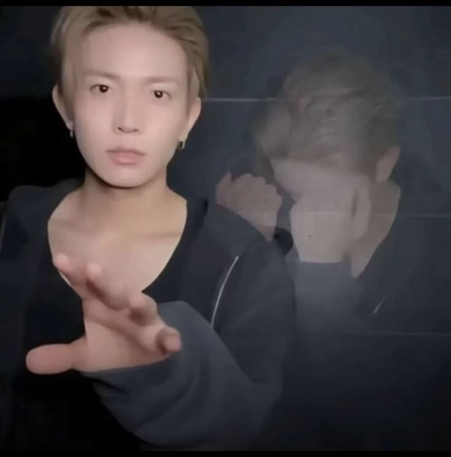Young Asian man with neutral expression reaching one hand toward the camera