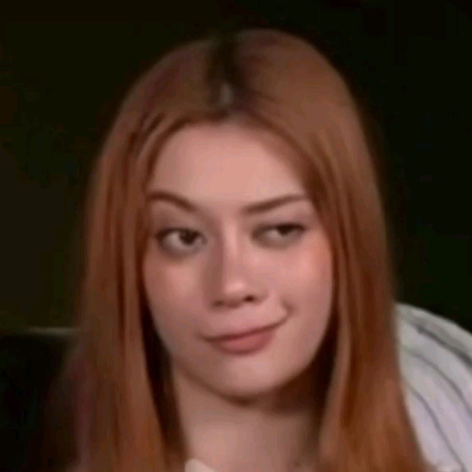 Redheaded woman with a subtle knowing smirk and amused side-eye