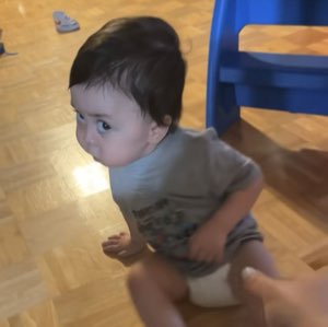 Baby looking sideways with a deeply skeptical side-eye as an adult holds them up
