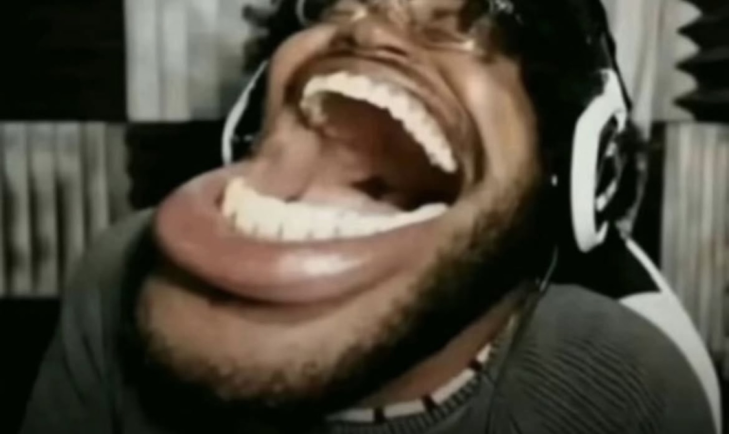 Man with headphones laughing hysterically with his mouth stretched wide open
