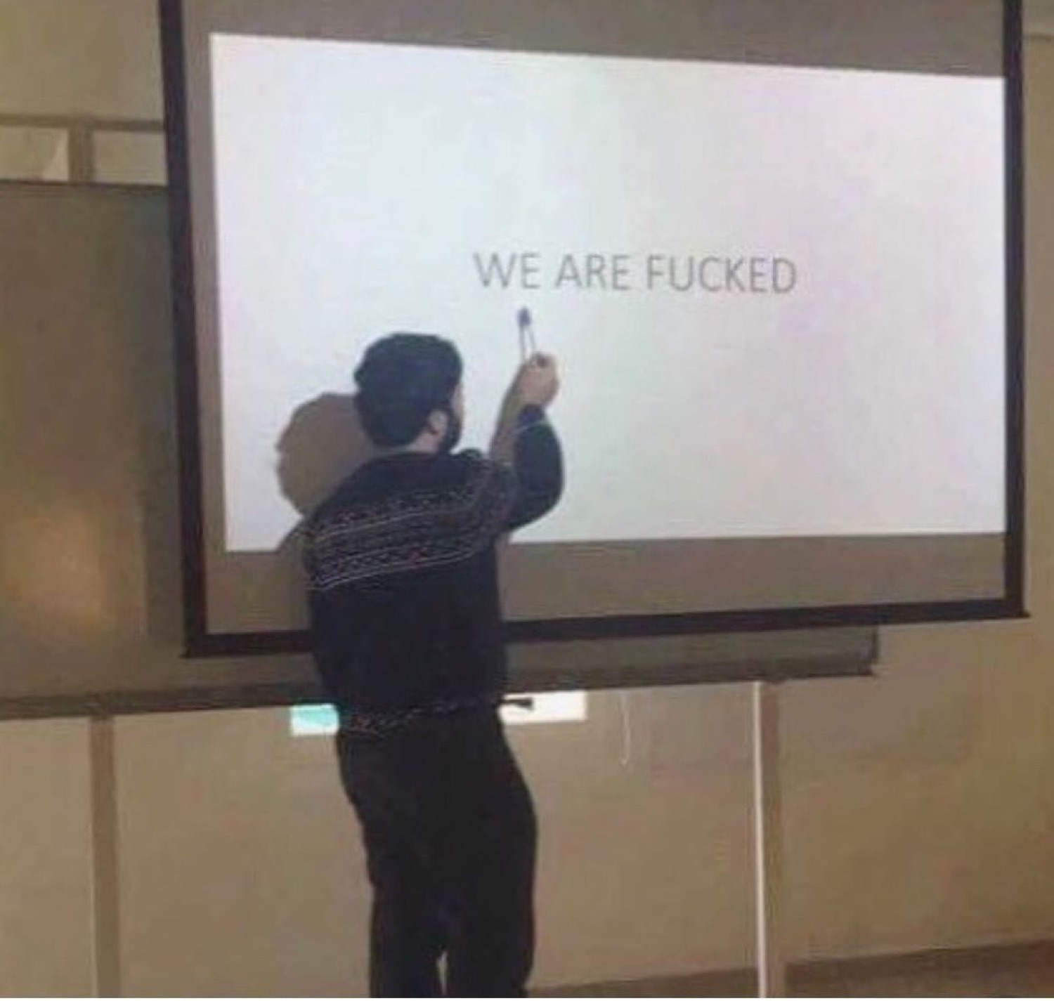 Person pointing at a projector screen displaying 'WE ARE FUCKED' in a lecture hall