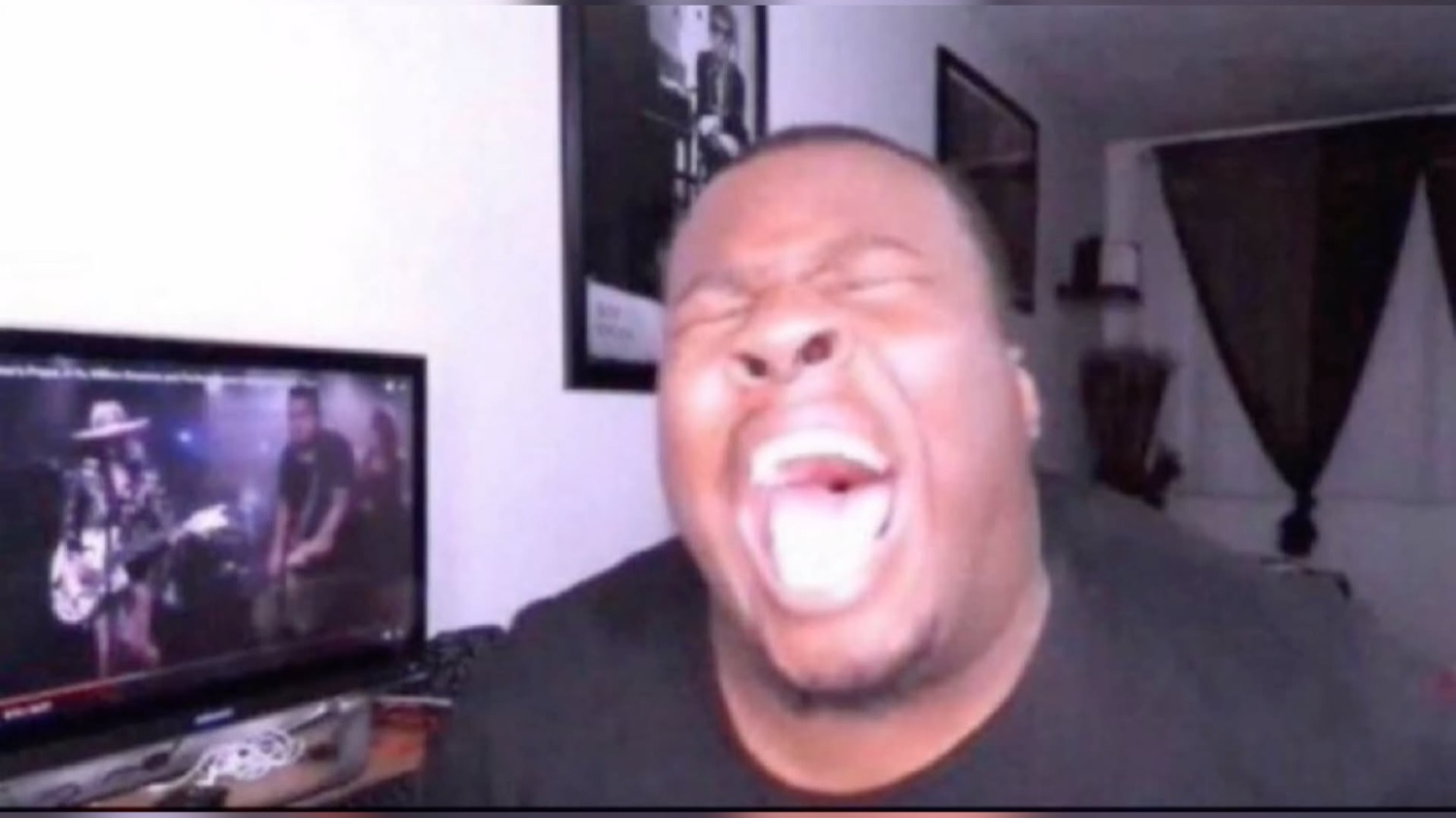 Guy in front of a TV throwing his head back mid-scream-laugh
