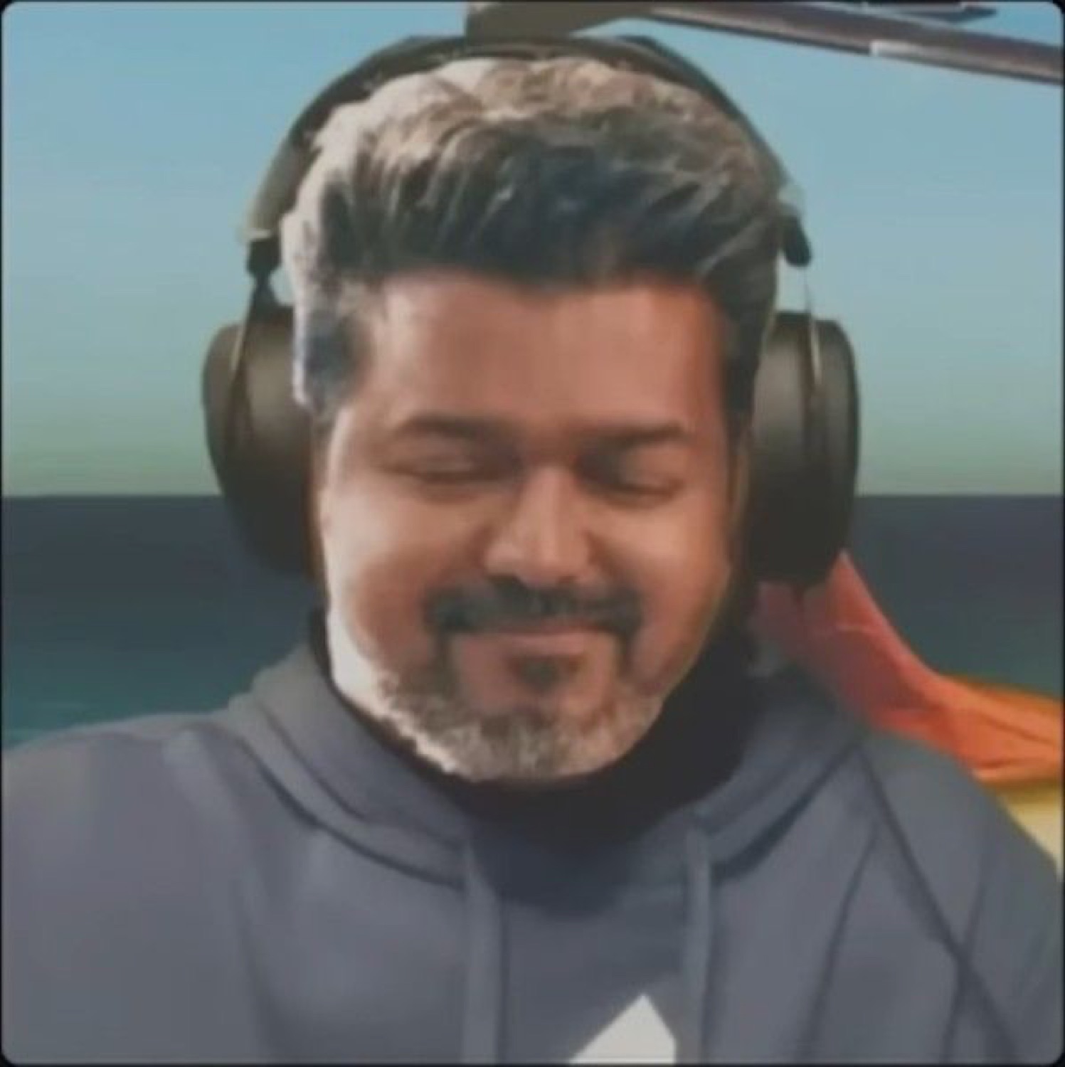Grey-haired Vijay in headphones smiling with his eyes closed