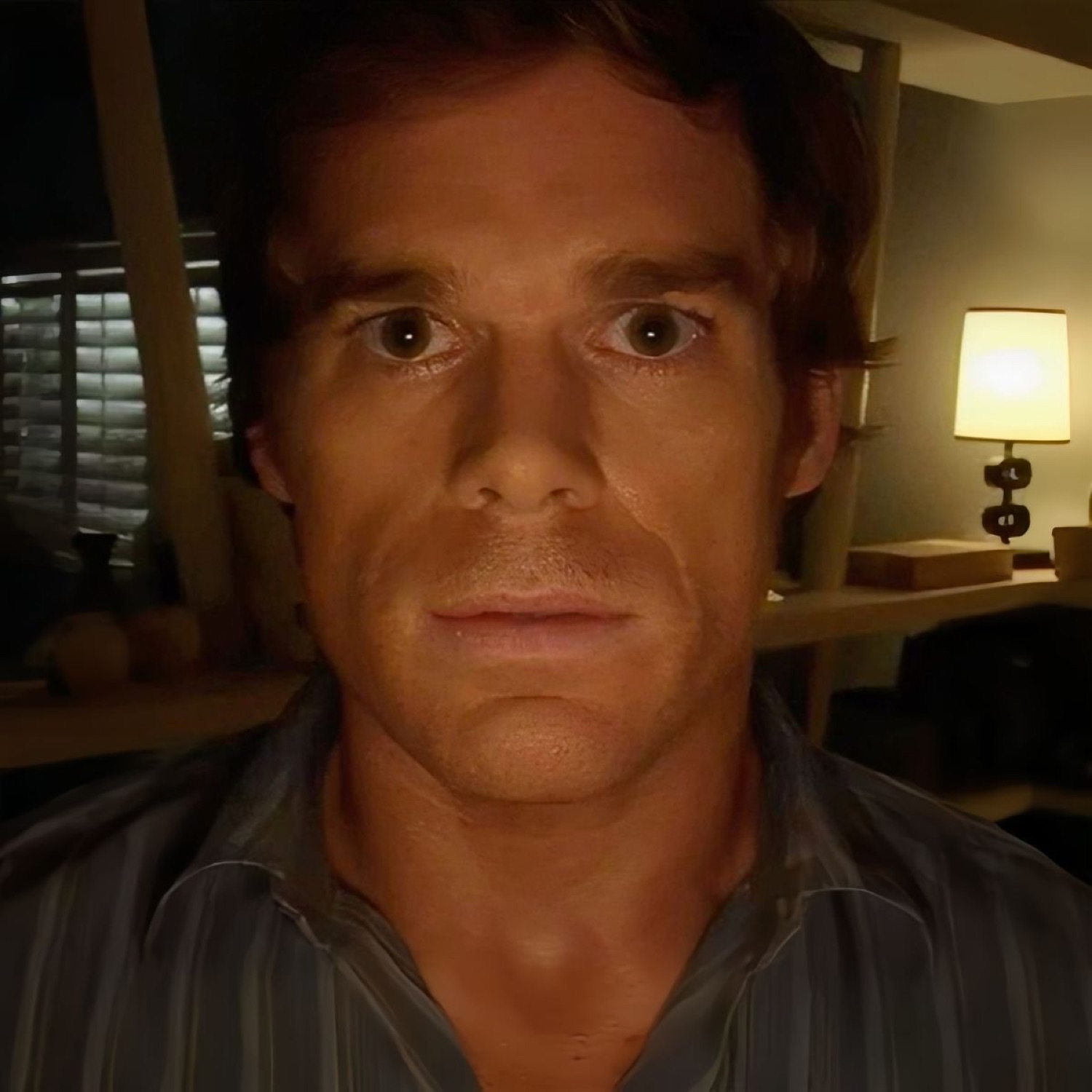 Dexter Morgan staring dead-eyed into your soul from a dimly lit room