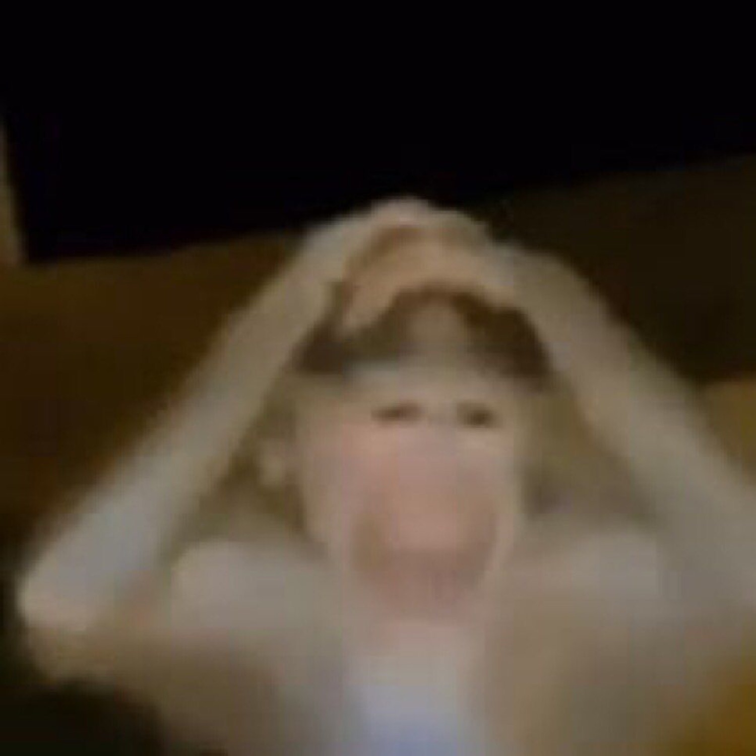 Blurry low-light shot of someone gripping their head with mouth wide open in distress