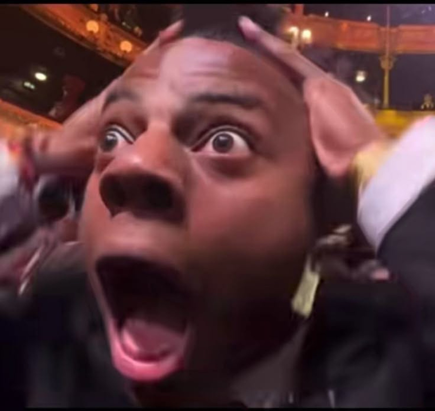 Man at a crowded event grabbing his head and screaming with massive wide eyes