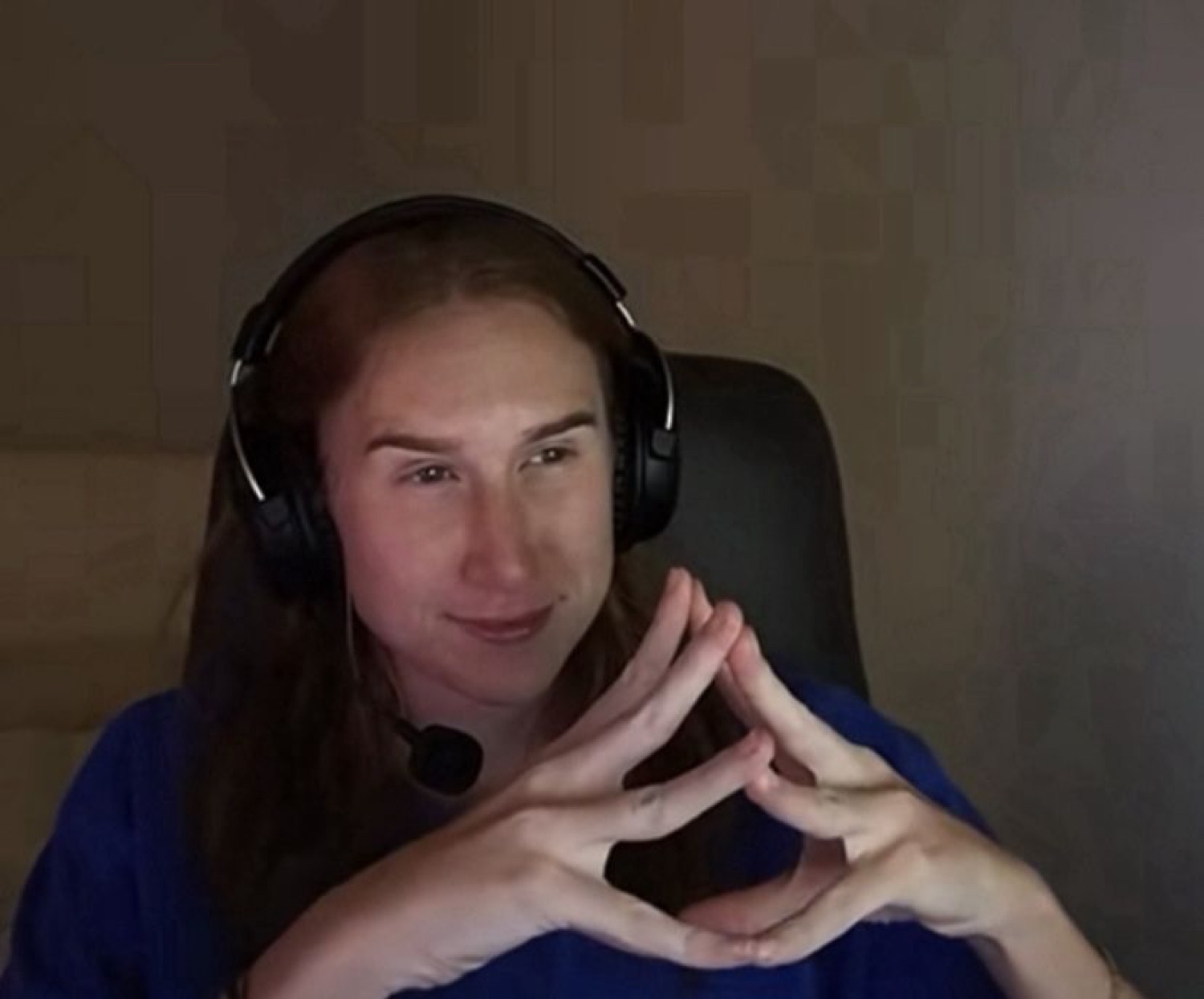 Streamer in a gaming headset with fingers steepled and a sly smirk, clearly scheming