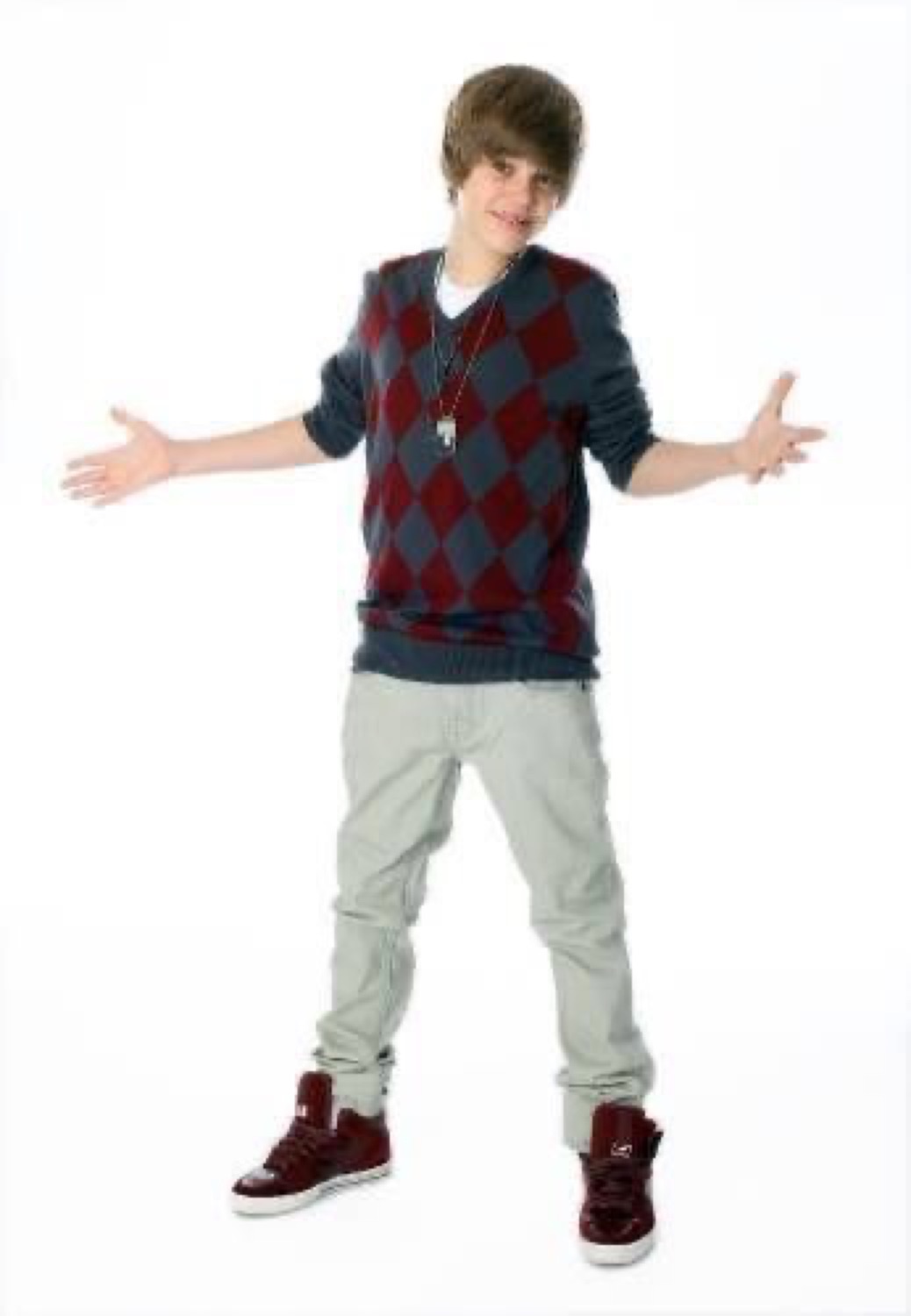 Young Justin Bieber in an argyle vest shrugging with both arms spread wide