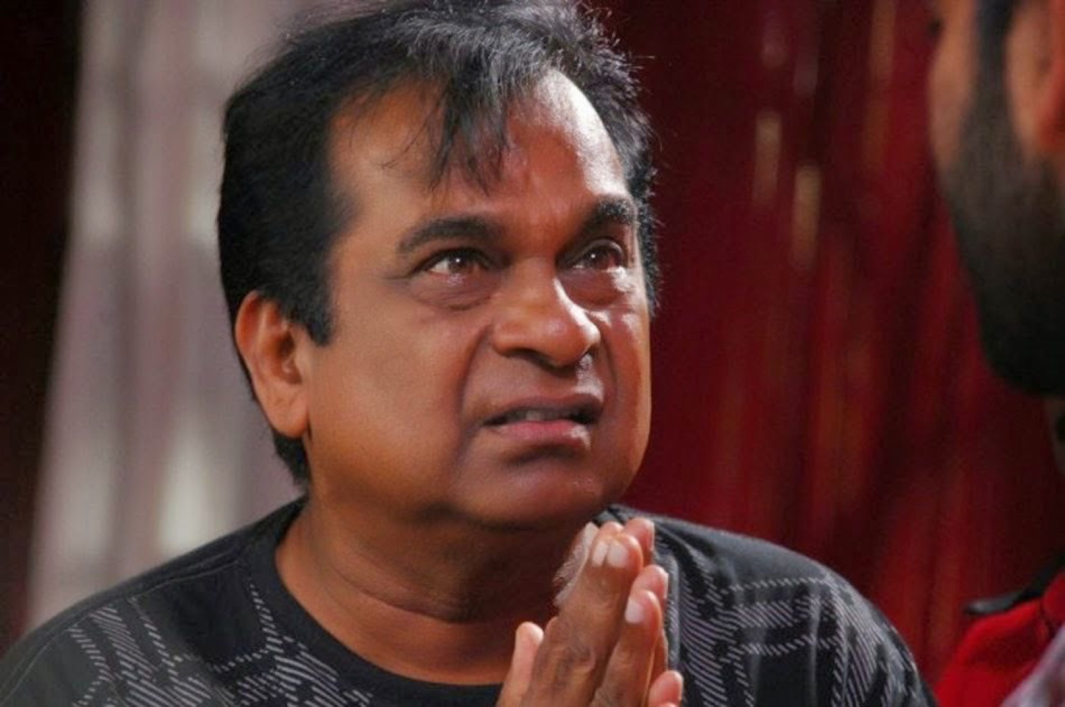 Brahmanandam pressing his palms together, pleading