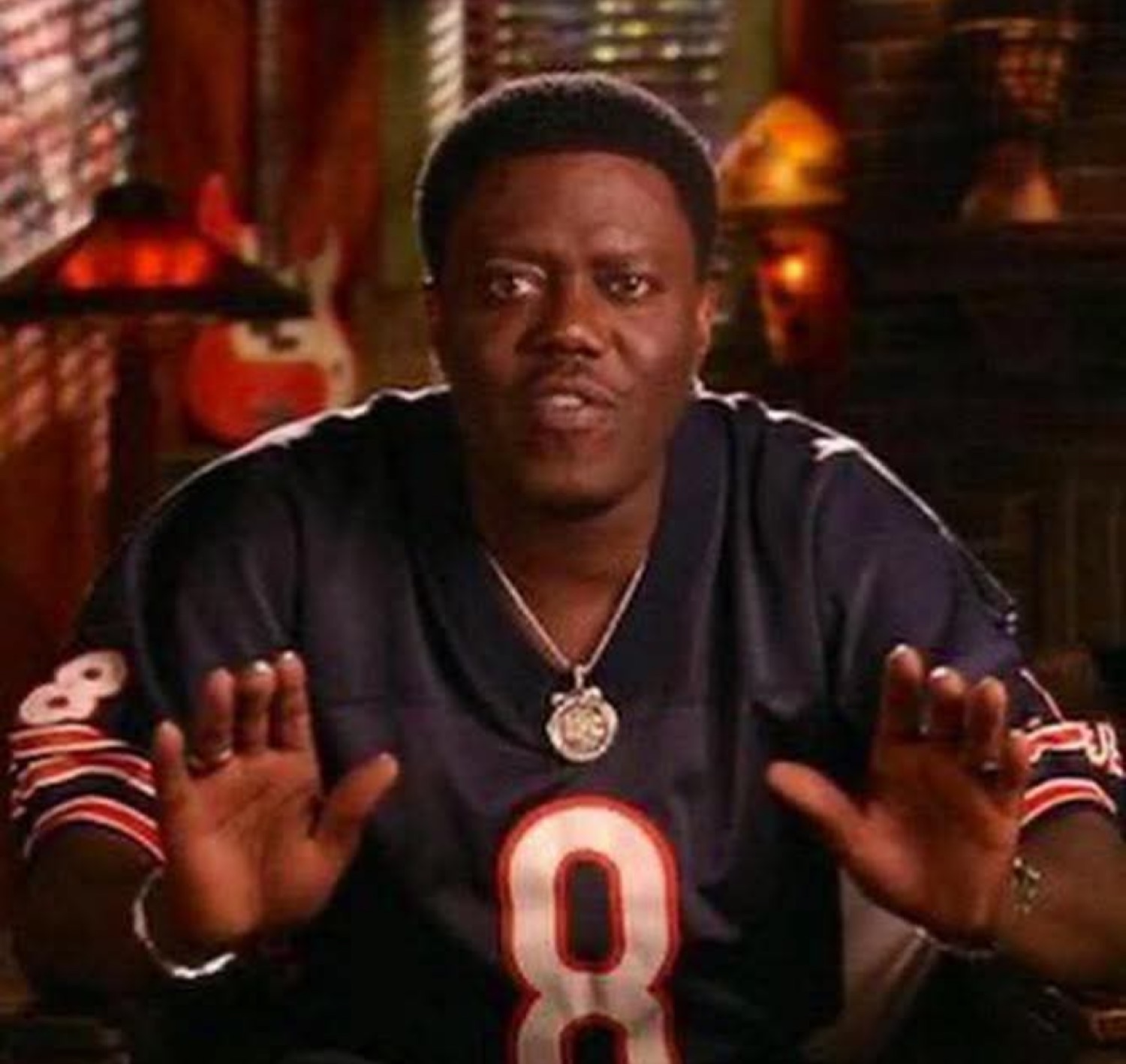 Bernie Mac in a Bears jersey holding up both hands like 'hold up'