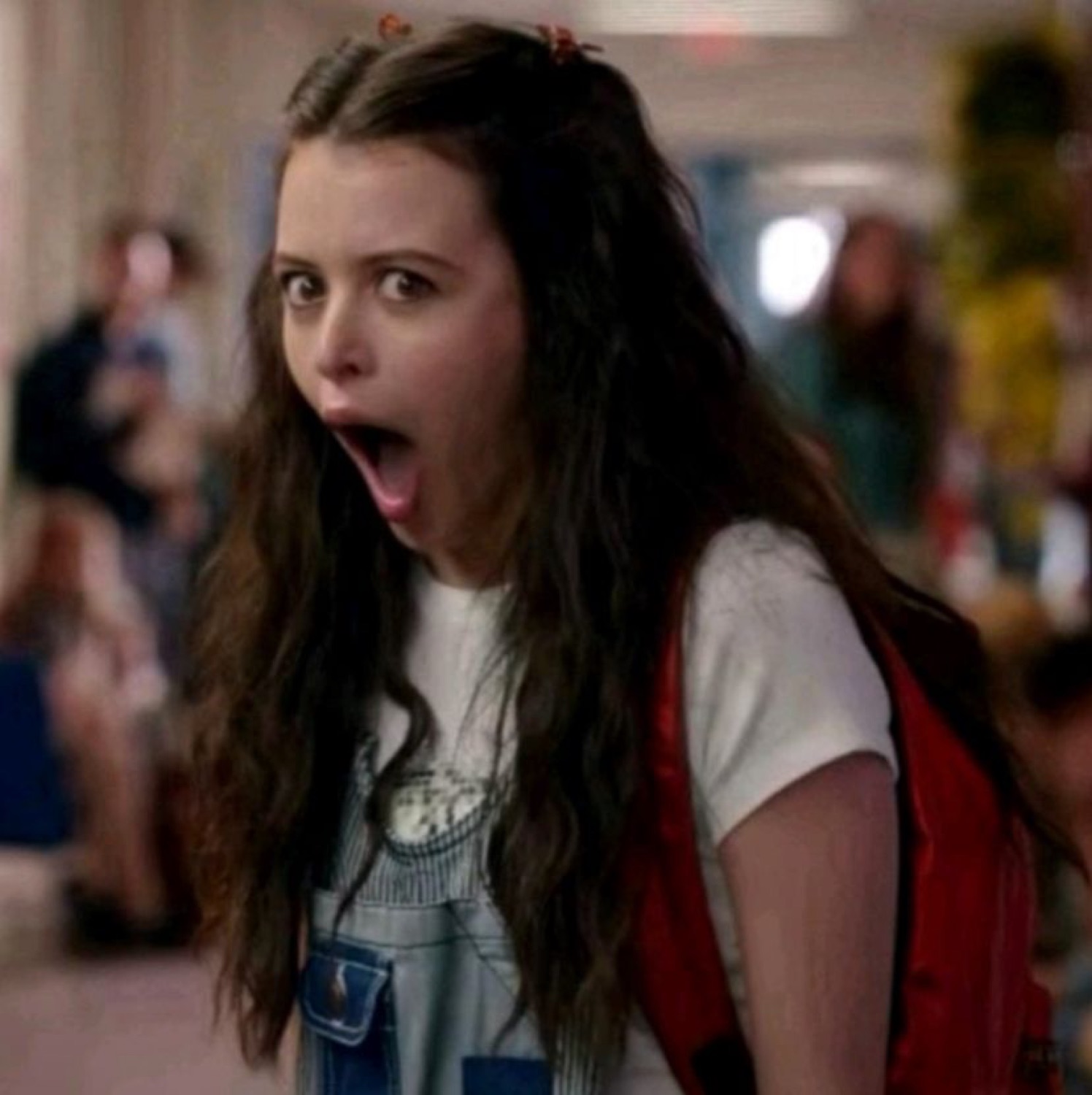 Teen girl in a school hallway with her mouth wide open in dramatic shock