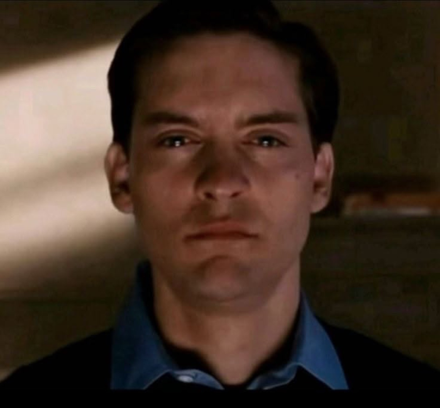 Tobey Maguire staring into the camera with a flat, empty deadpan expression