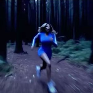 Woman sprinting through a dark forest
