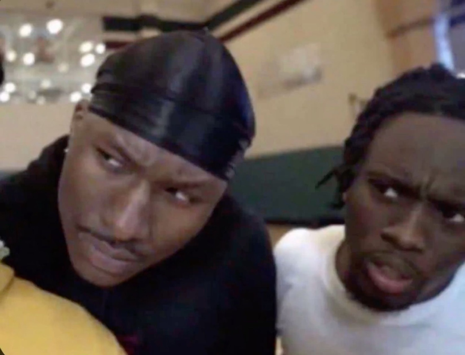 Two guys leaning into the camera, one side-eyeing and the other looking deeply unconvinced