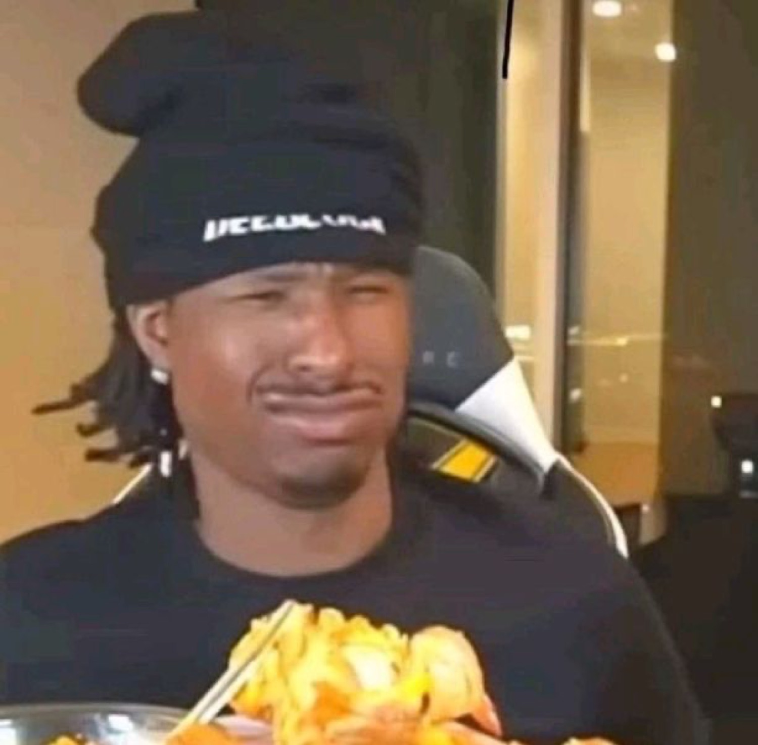Man in a beanie scrunching his face in disgust over a plate of food