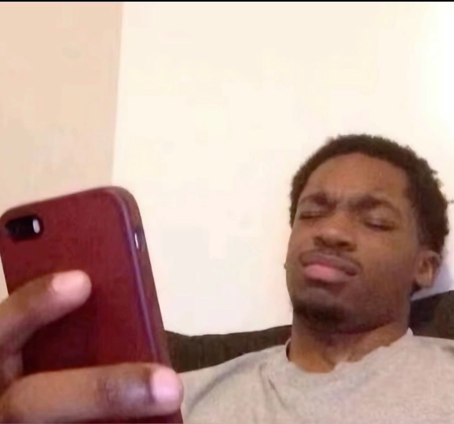 Guy lying on a couch barely looking up from his phone with heavy lidded eyes