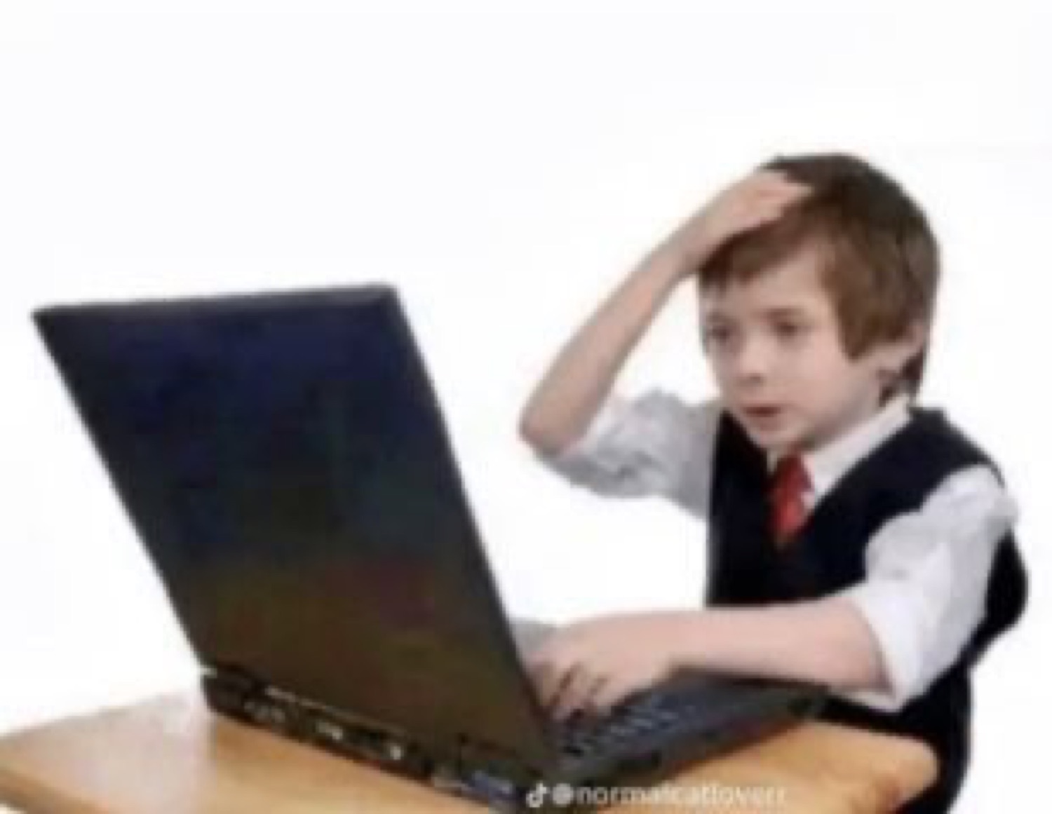 Young boy in suit and tie at a laptop, hand on head, staring in shock at the screen