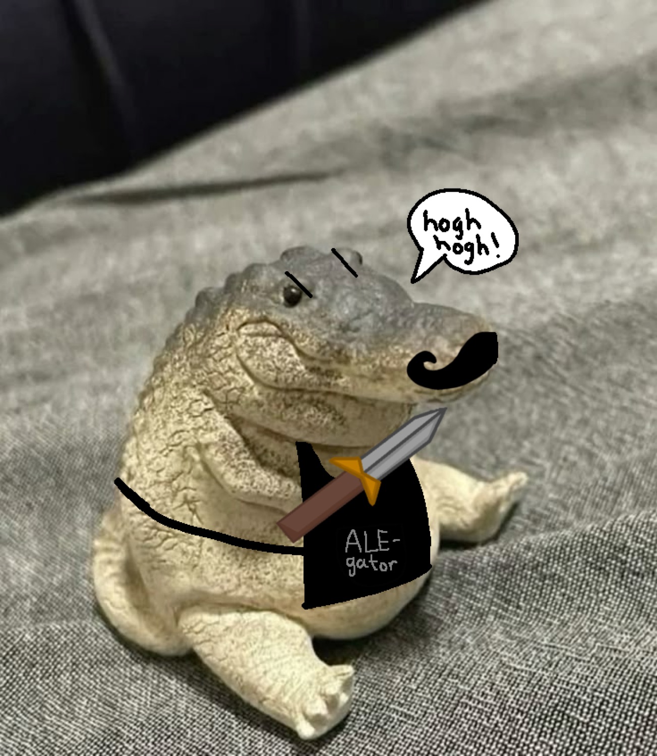 Chubby alligator figurine with a mustache saying 'hogh hogh' in an 'ALE-gator' shirt