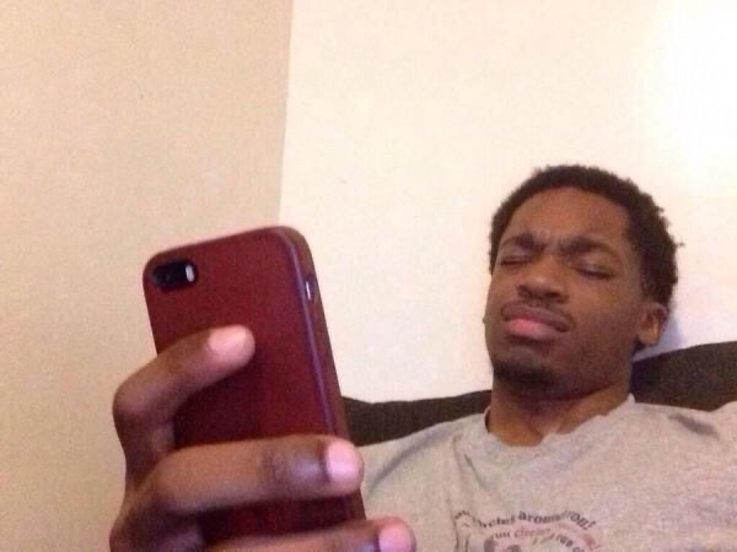 Guy lying on a couch giving a squinting side-eye at his phone like it personally offended him