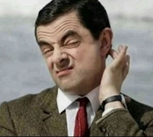 Mr. Bean scratching his ear with a cringing, skeptical face