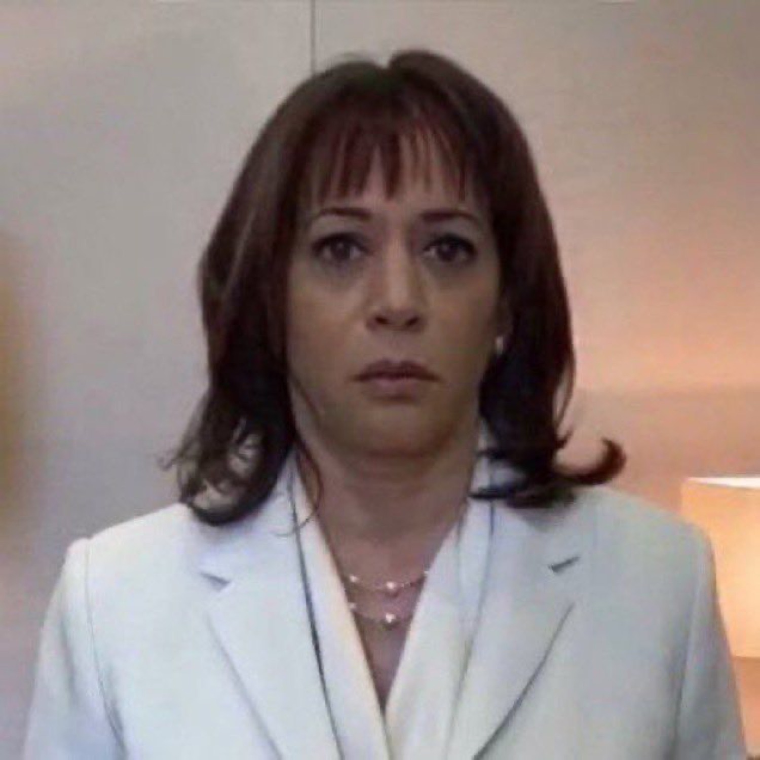 Woman in a white blazer staring blankly at the camera, completely deadpan