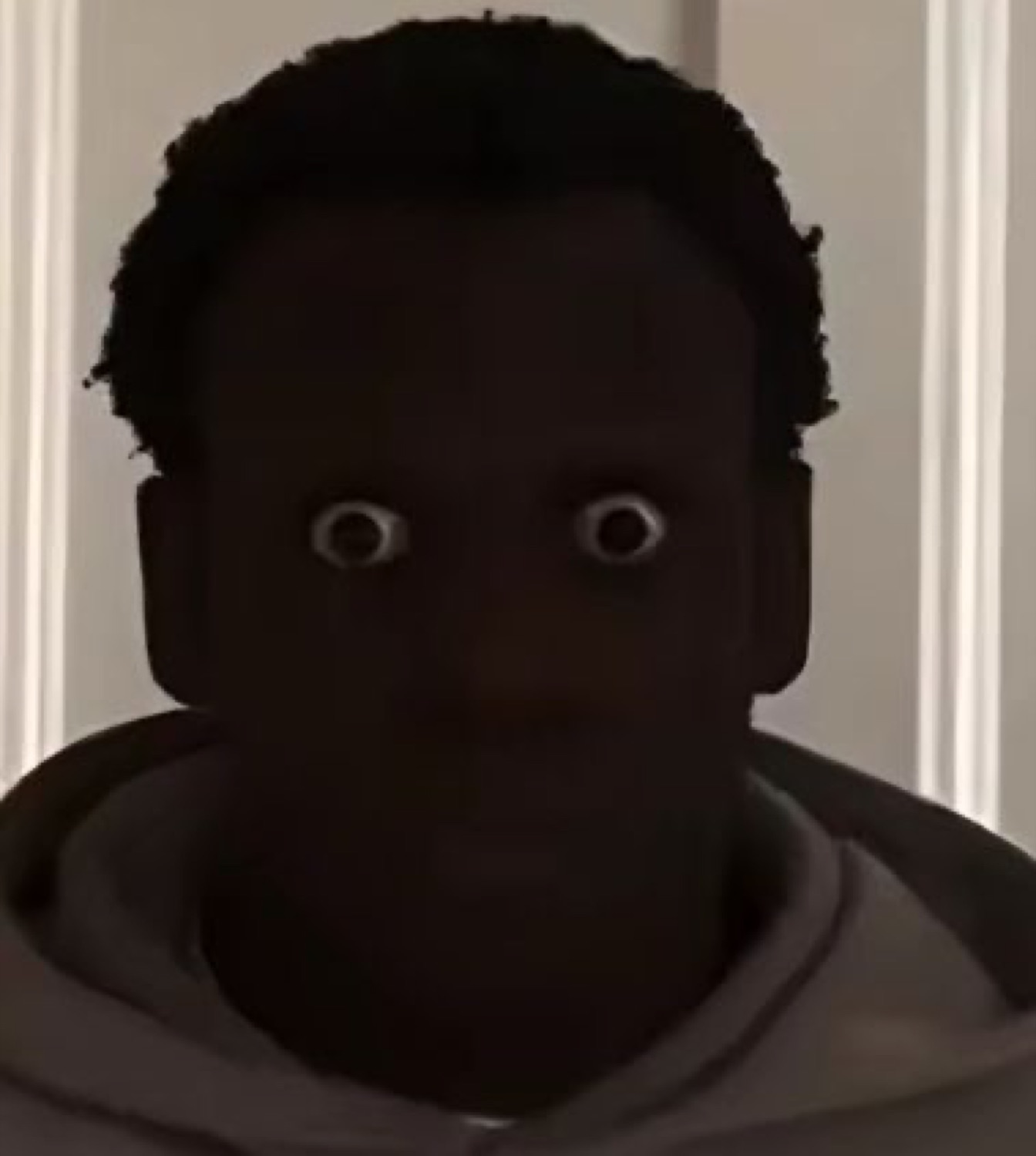 Person in shadow with only wide white eyes visible, looking startled