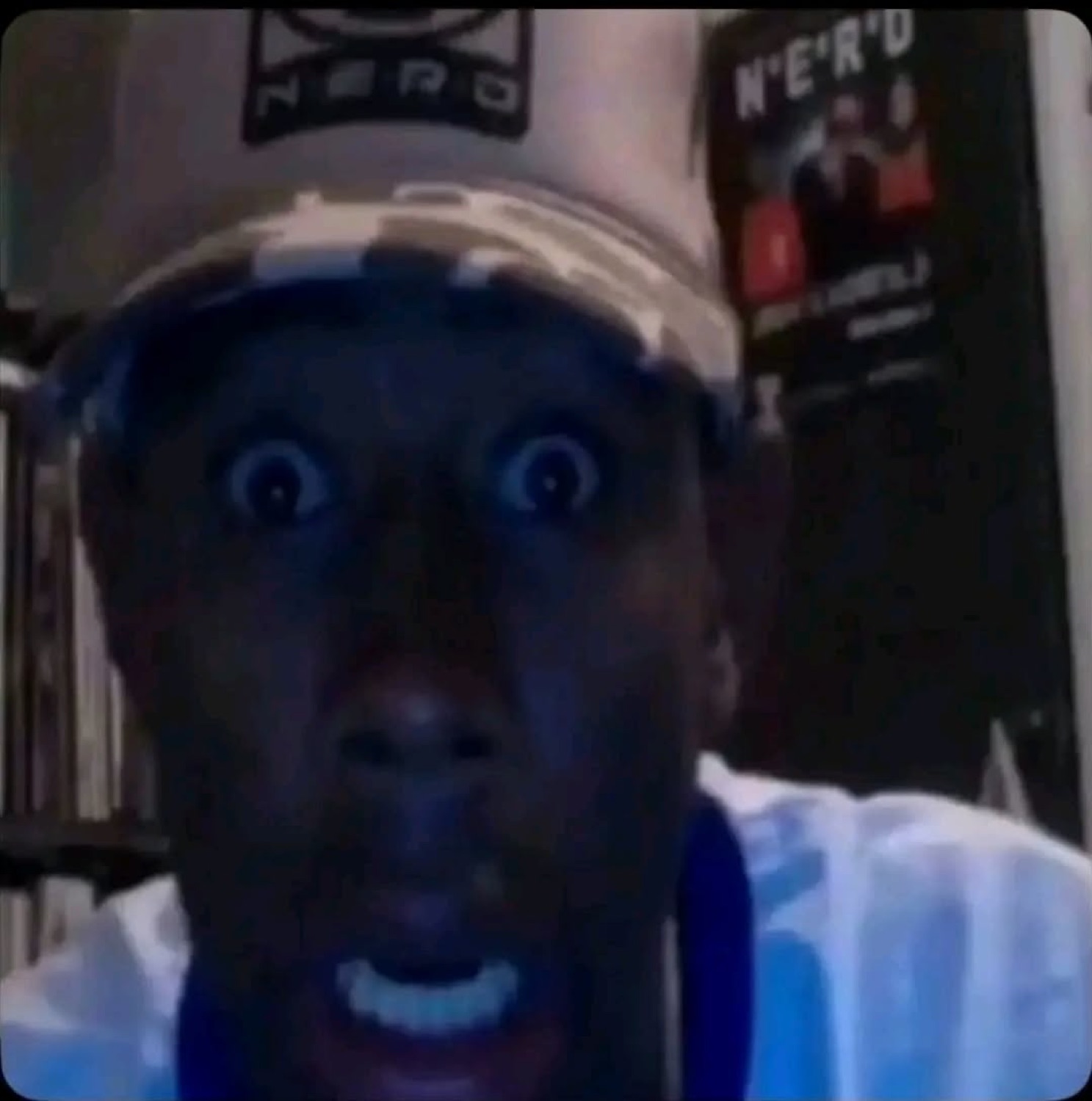Man in a cap staring into the camera with enormous white-lit wide eyes and mouth agape