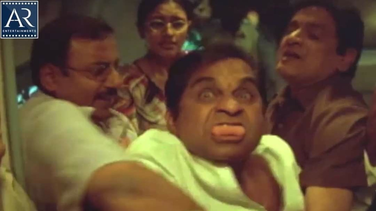 Brahmanandam puffing his cheeks as men hold him back
