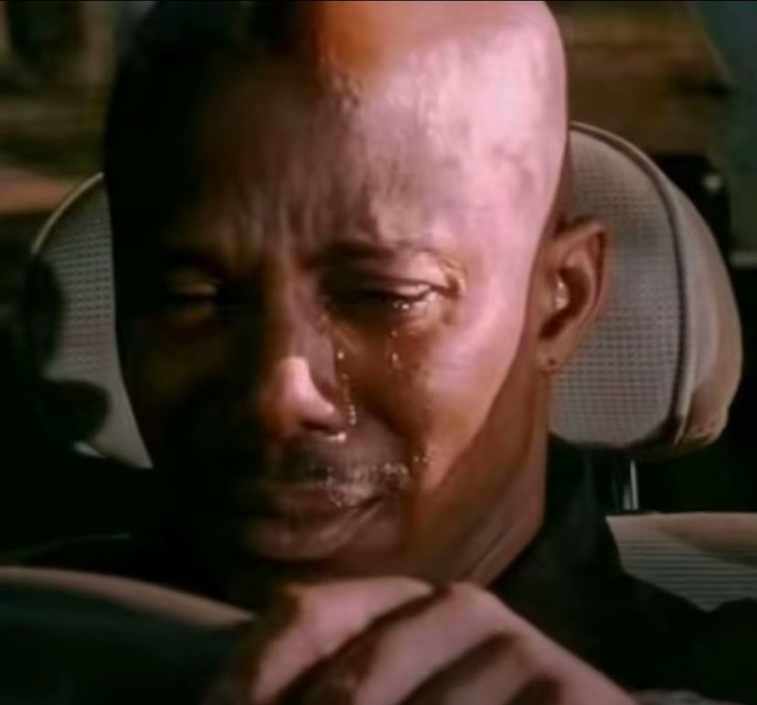 Man in a car seat with silent tears streaming down his face