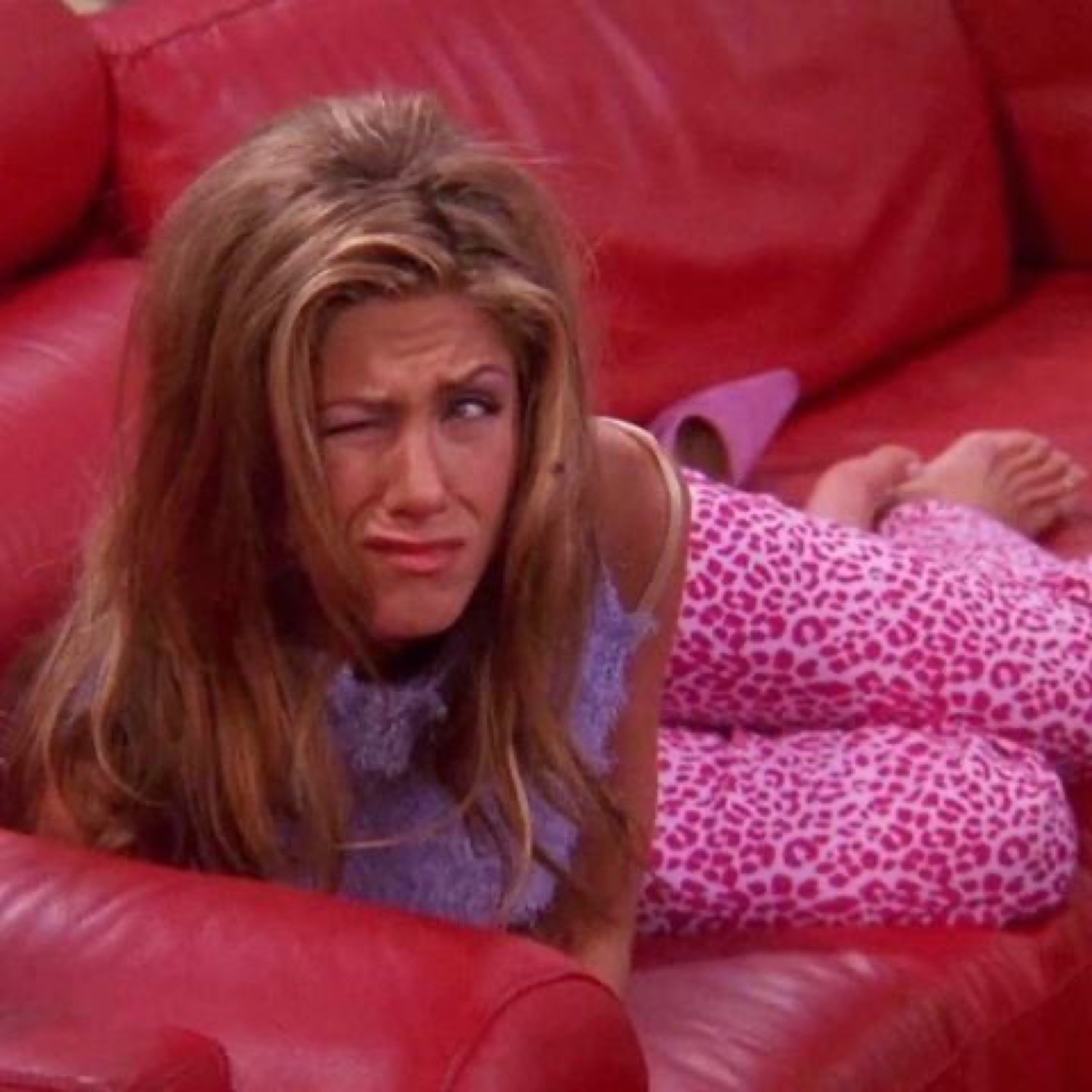 Rachel from Friends wincing on a red couch