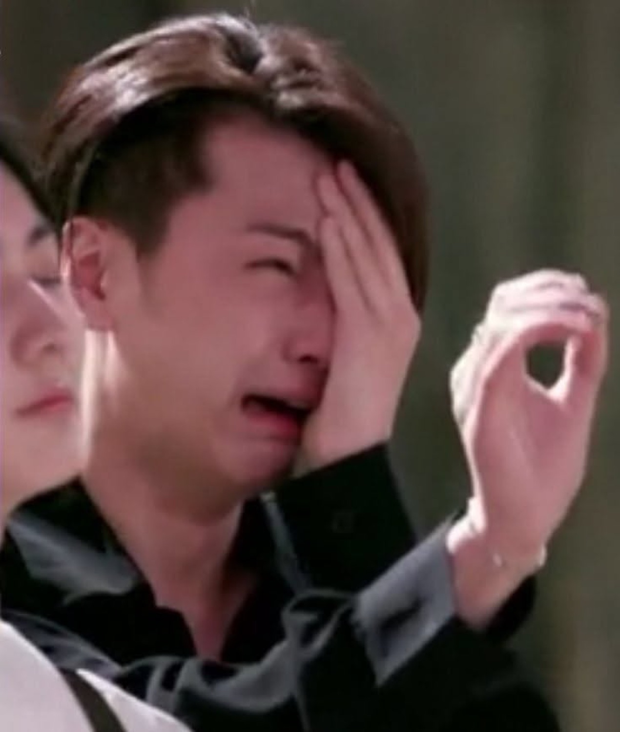 Man sobbing openly with one hand shielding half his face
