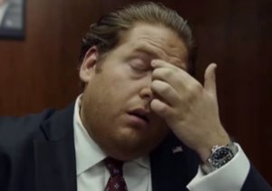 Man in a suit pinching the bridge of his nose in tired frustration