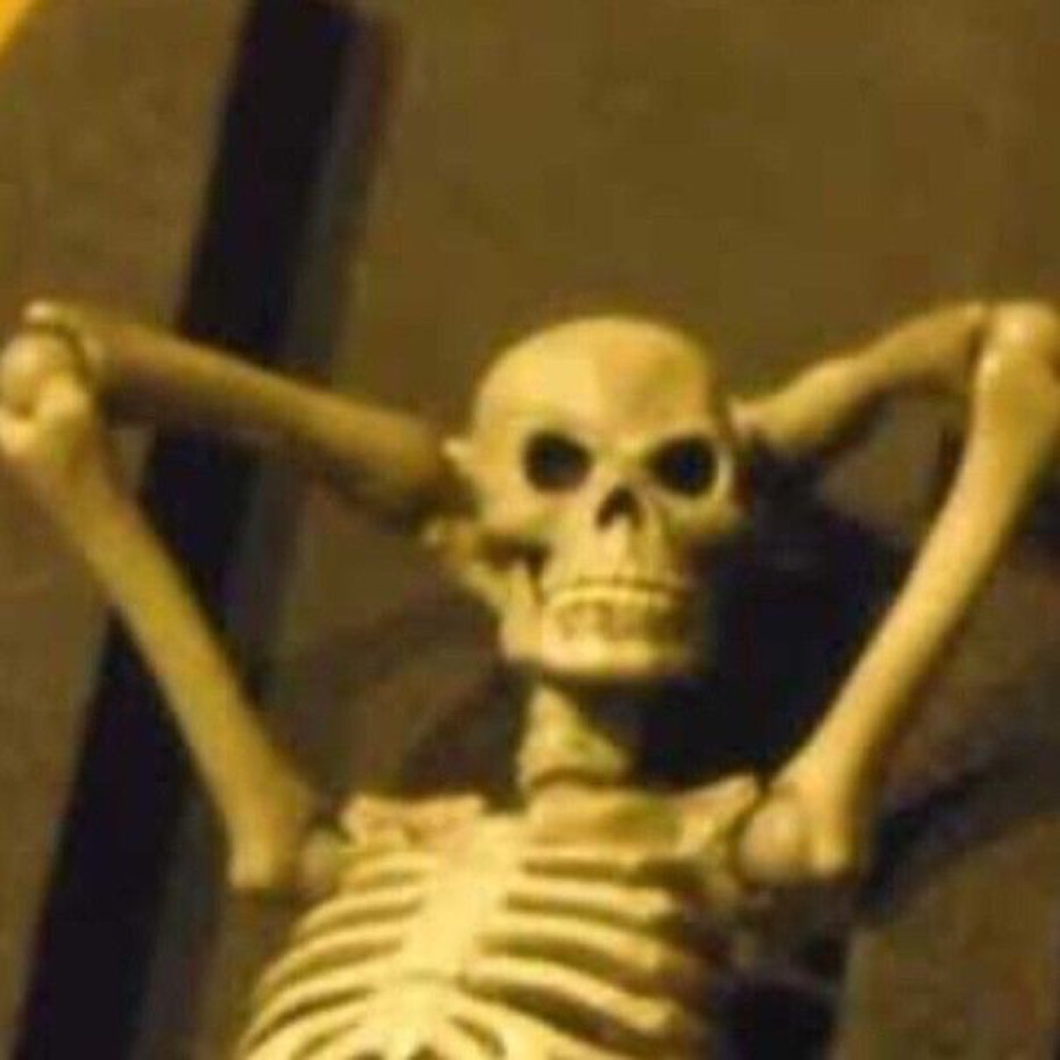 Grinning skeleton leaning back with its hands behind its head