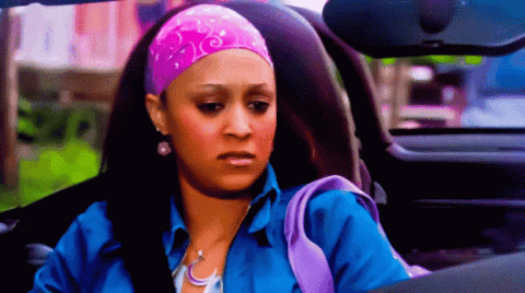 Woman in a pink headscarf sitting in a car looking down with a disappointed, fed-up expression