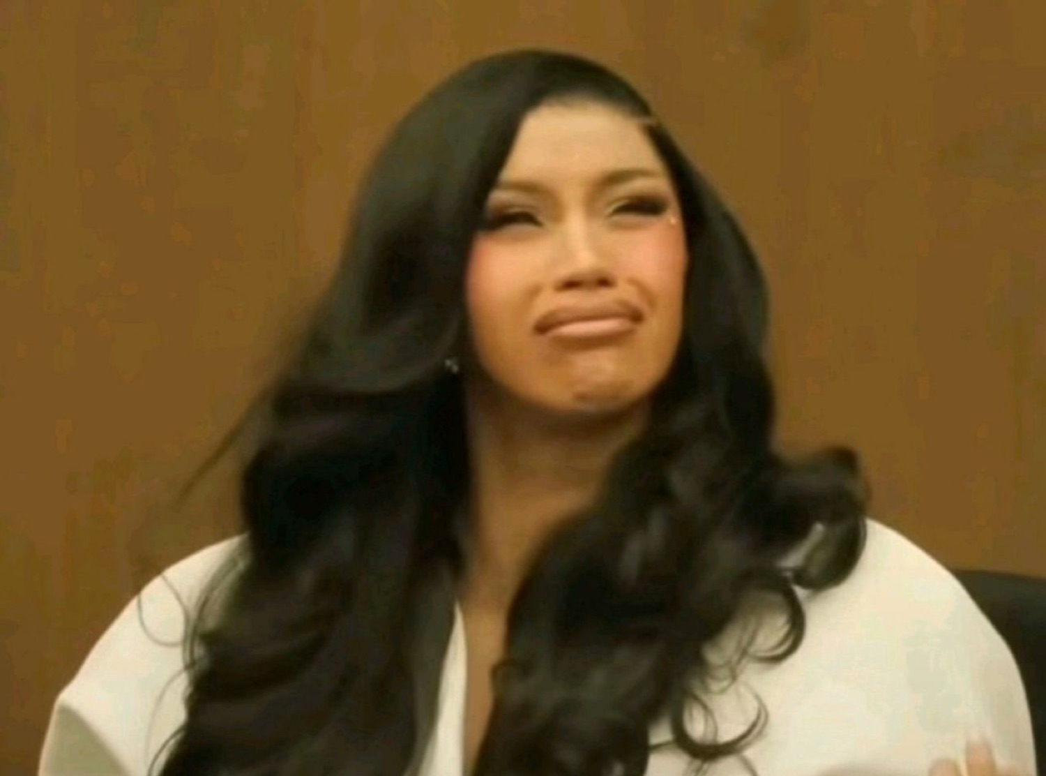 Woman with long black hair making a pained, cringing smile while trying to hold it together
