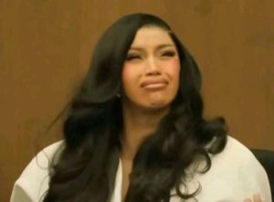 Woman with long black hair making a pained, cringing smile while trying to hold it together