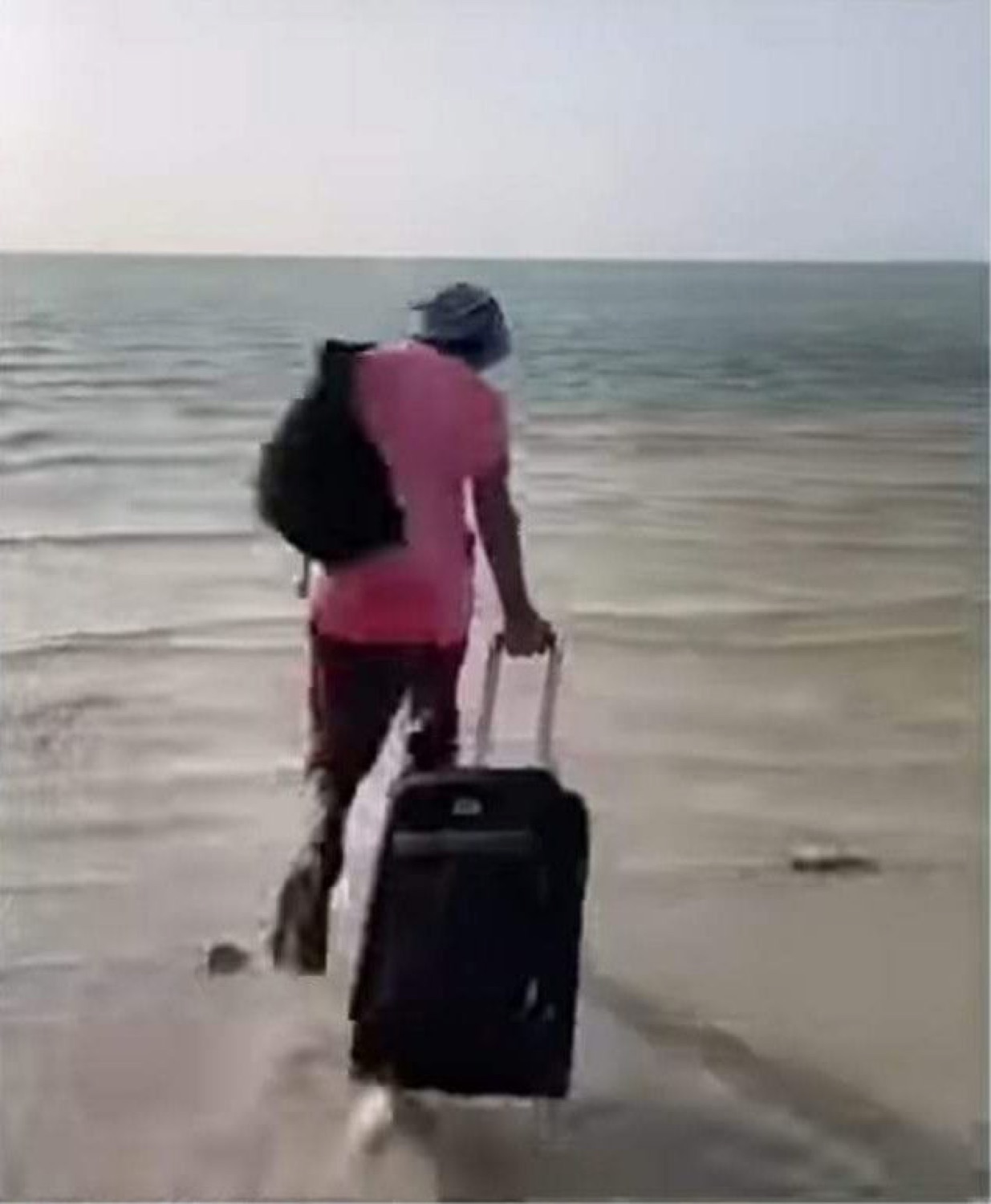 Man wheeling his suitcase straight into the sea