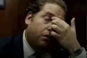 Man in a suit pressing his palm hard into his face, fully done with everything