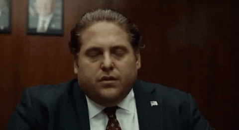 Jonah Hill in a suit blinking slowly with a completely deadpan, unimpressed stare