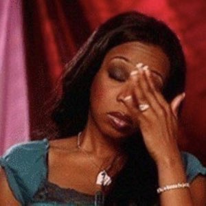 Woman in a teal top pressing her hand to her face with her eyes closed in exhaustion