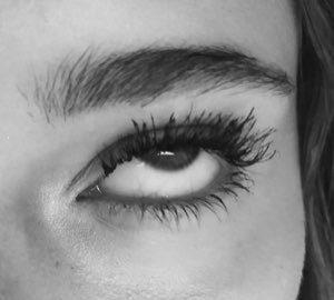 Extreme close-up of a wide-open eye with dramatic lashes in black and white
