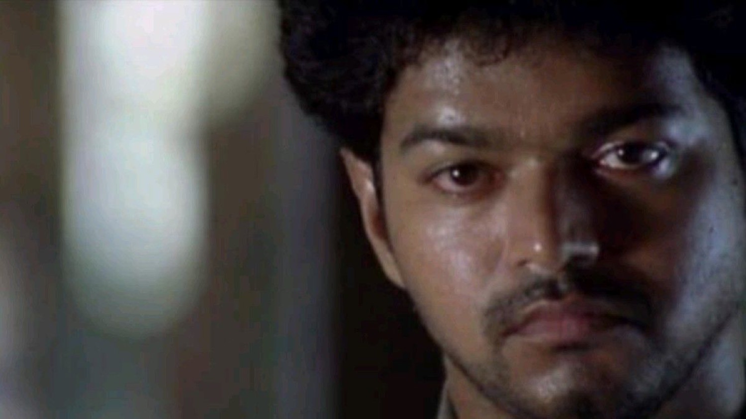 Vijay glaring intensely in dim light