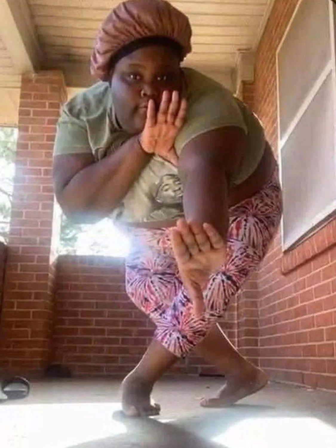 Woman in a bonnet crouching in shock on a porch with both hands covering her mouth