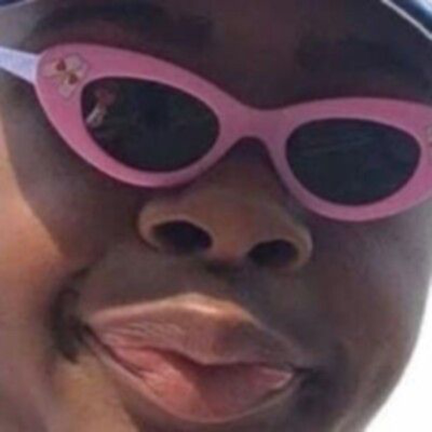 Guy in pink cat-eye glasses pursing his lips