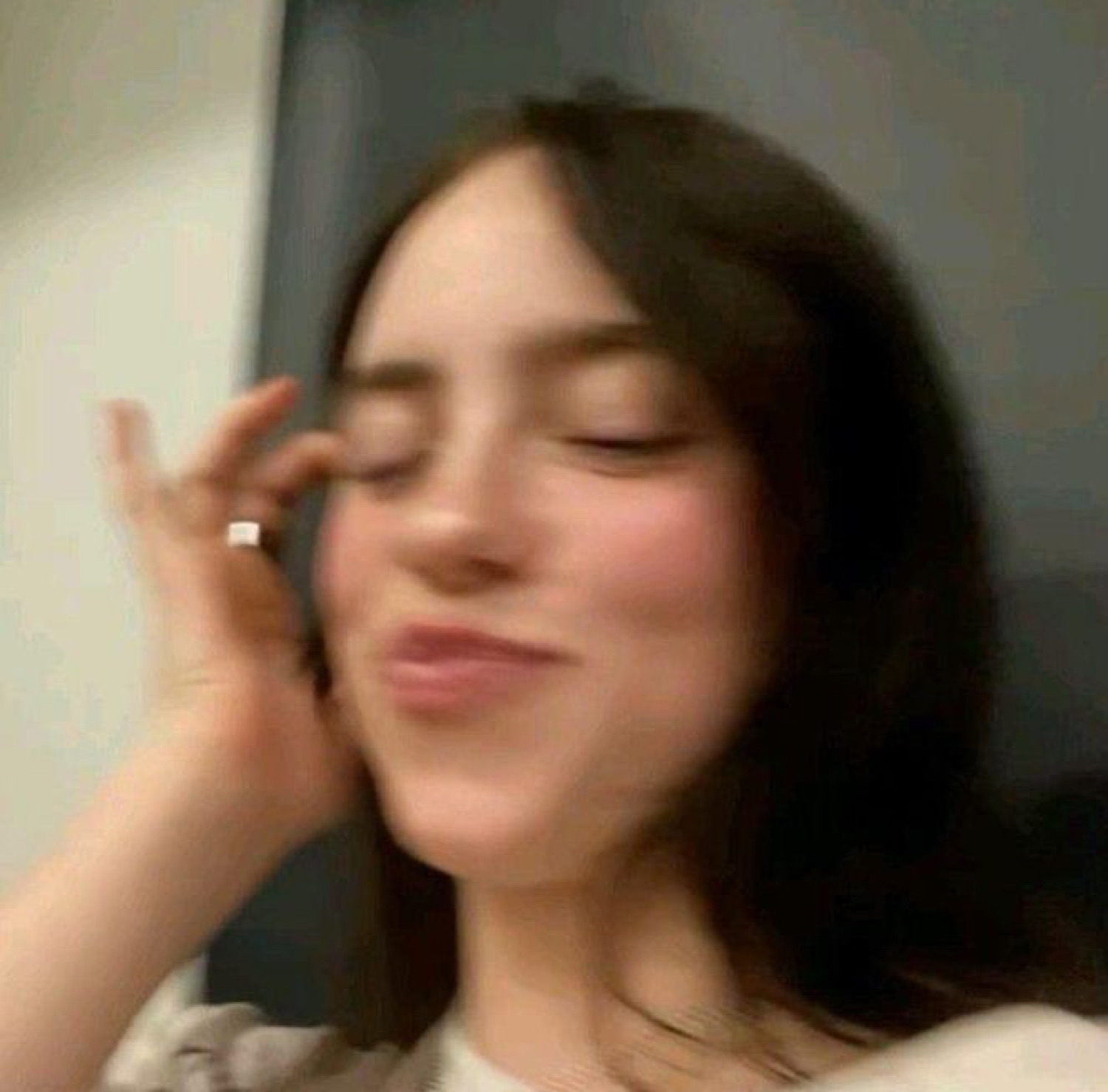 Blurry selfie of a woman with a smug, satisfied little smirk and closed eyes