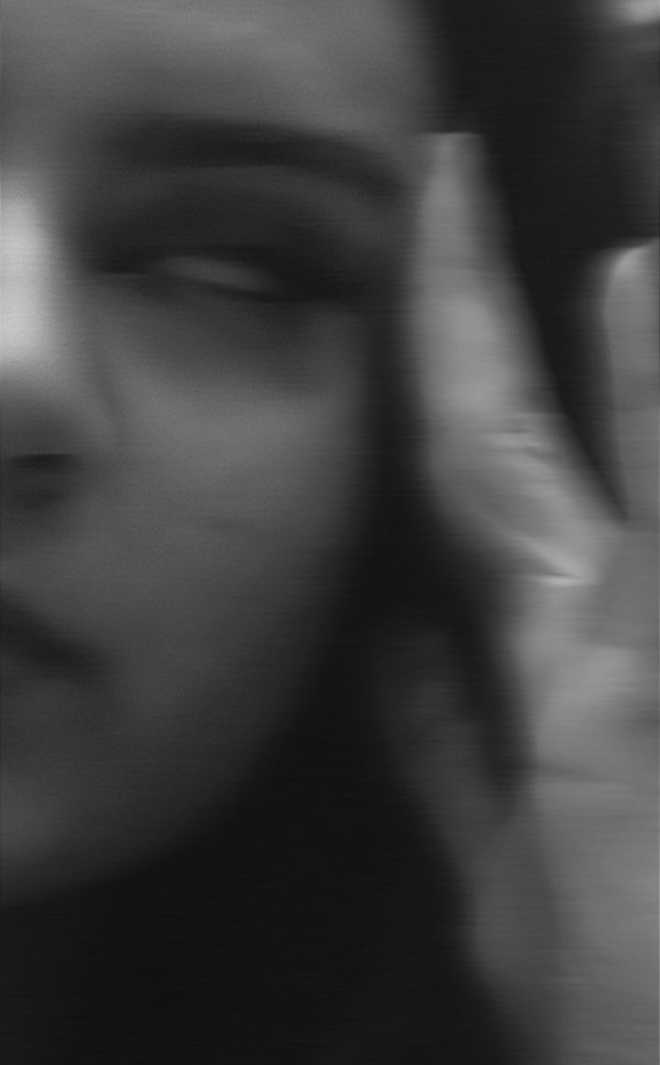 Dark, grainy shot of a woman cutting a sharp sideways glare past her hand