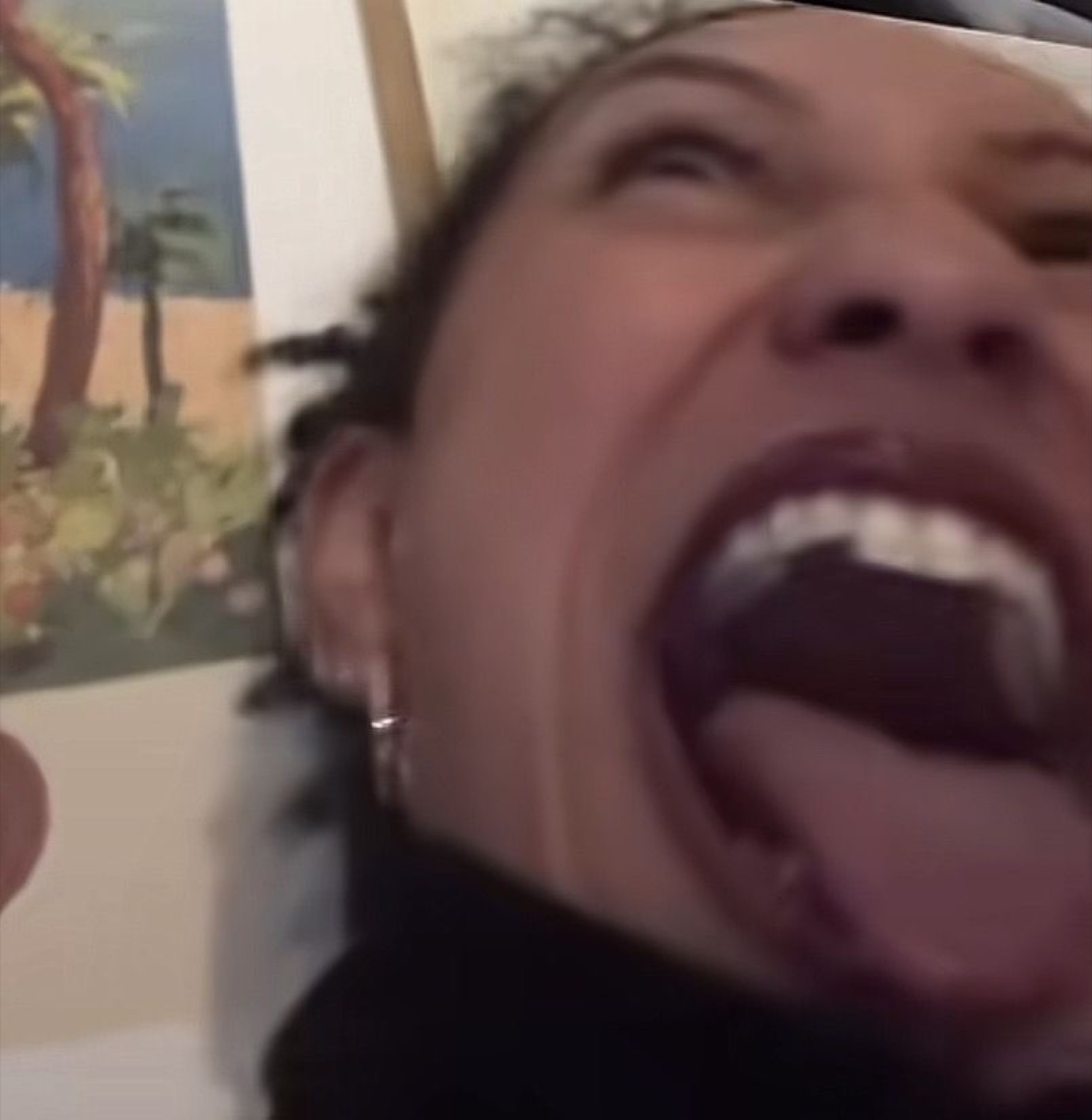 Extreme close-up of a person mouth wide open mid-scream, tongue out and eyes squeezed